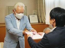 同館の大西宏明館長に目録を手渡す東谷事務局長(左)=明和町竹川の斎宮歴史博物館で